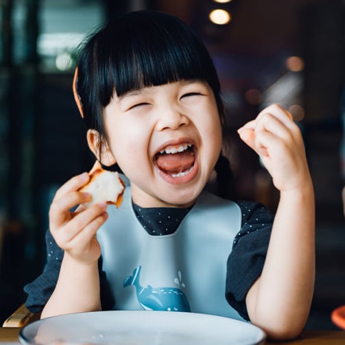 Small child smiling with food in their hand