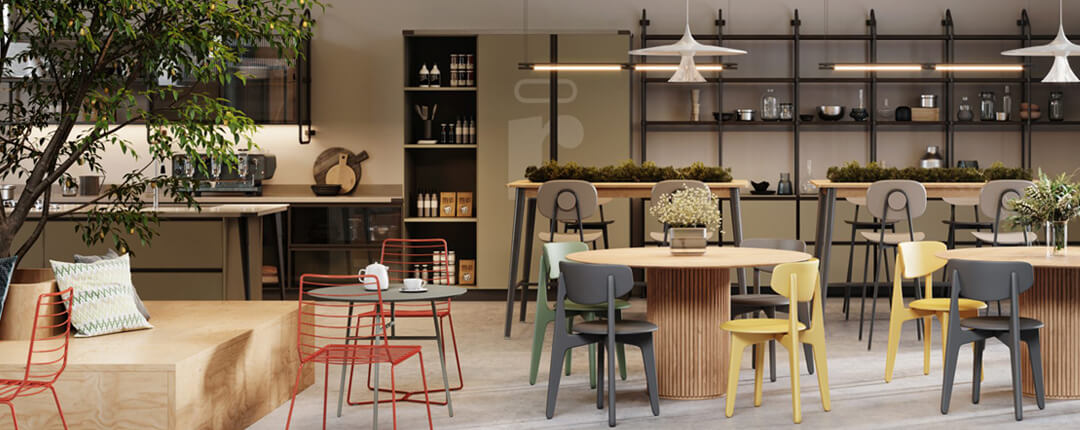 Modern café-style space with wooden tables, colorful chairs, open shelving, and plants creating a cozy atmosphere.