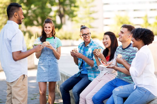 Group of students eating and socializing outdoors.