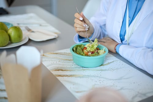 A healthcare employee eating a salad.