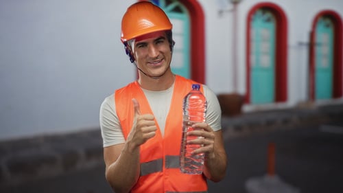 Construction worker holding a water bottle and giving a thumbs up.