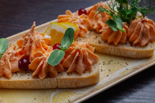 Crostini topped with creamy spread, herbs, lemon, and cranberries.
