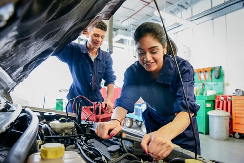 A man and a woman working on a car.