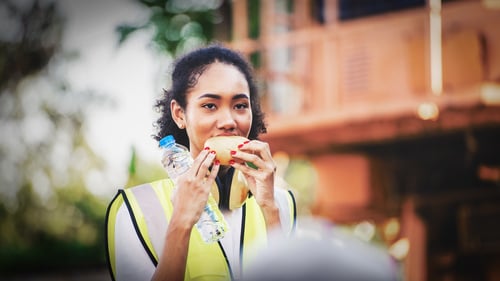 A woman eating a snack and holding a water bottle.
