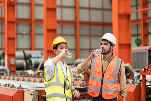 Two manufacturing employees drinking a bottle of water.