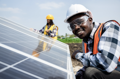A man smiling near a solar panel.
