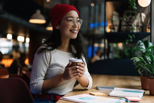 A woman smiling and drinking coffee at a trade school.