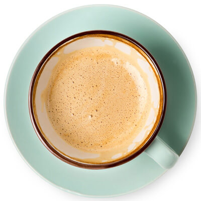 Top view of a frothy coffee in a brown-rimmed cup on a light green saucer.