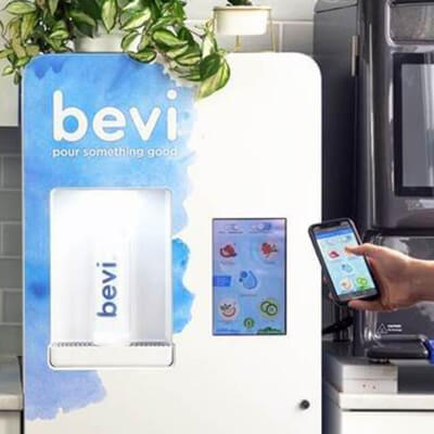 Bevi hydration machine with a person selecting drink options using a smartphone.