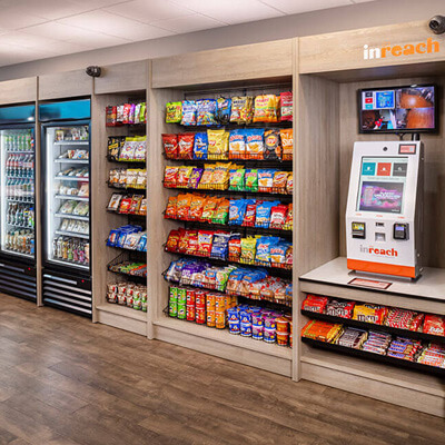 Snack shelves, drink coolers, and a self-checkout kiosk in a modern micro‑market setup.