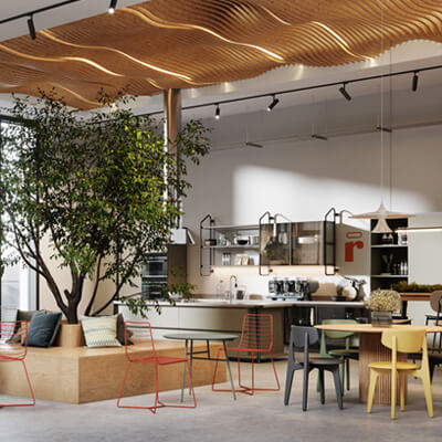 Modern lounge with trees, colorful chairs, large windows, and a kitchen area with coffee machines and shelving.