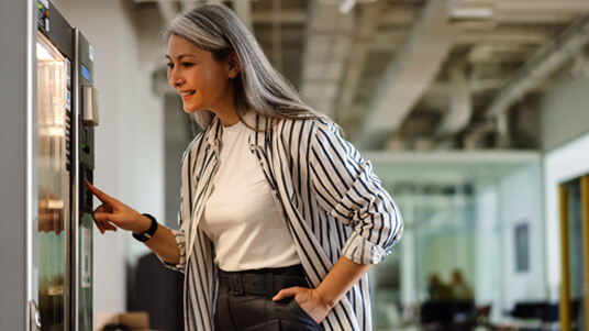 A woman selecting a snack from a vending machine