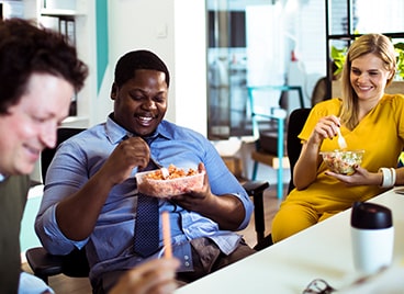 People sitting together in an office eating lunch and talking.