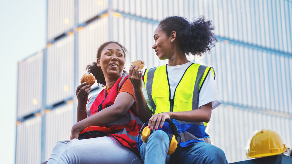 Two women eating a snack on their lunch break.