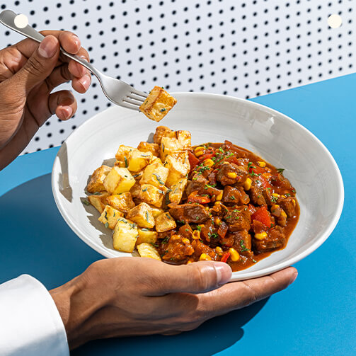 A person enjoying a bowl of food using a fork to savor their meal