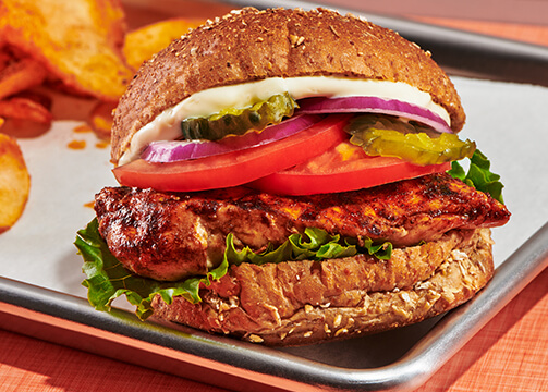 A delicious chicken sandwich served on a soft bun garnished with fresh lettuce and a slice of tomato