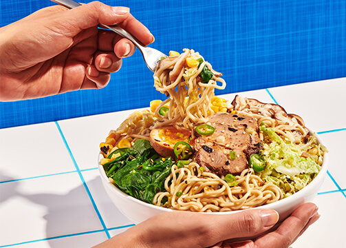 A person holds a fork above a bowl filled with food