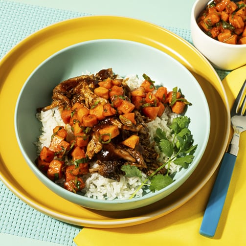 A plate of rice topped with seasoned meat, garnished with herbs, served on a white dish.