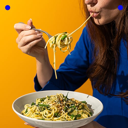 A woman enjoying a plate of spaghetti twirling the pasta with a fork