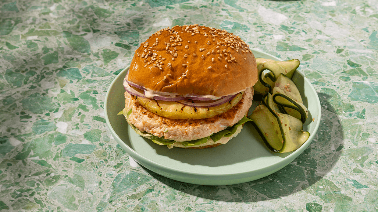 Hawaiian salmon burger on a seeded bun with grilled pineapple and sweet soy aioli.