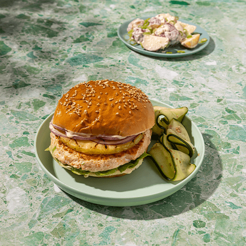 Hawaiian salmon burger on a seeded bun with grilled pineapple and sweet soy aioli.