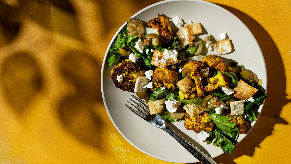 Turmeric roasted cauliflower with wilted escarole and feta, olive-brined pickled mustard seed vinaigrette, and pita croutons