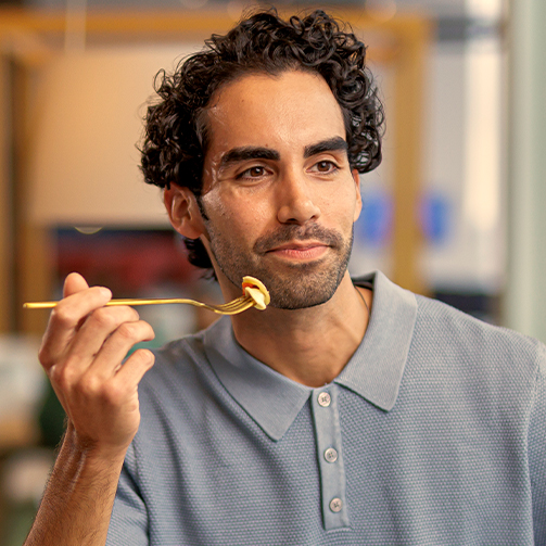 Person holding a fork and eating while seated in a casual dining setting.