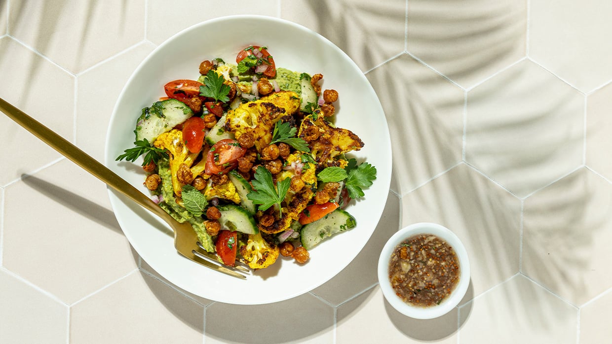 A plate of food accompanied by a spoon and a bowl of sauce, ready for serving and enjoyment.