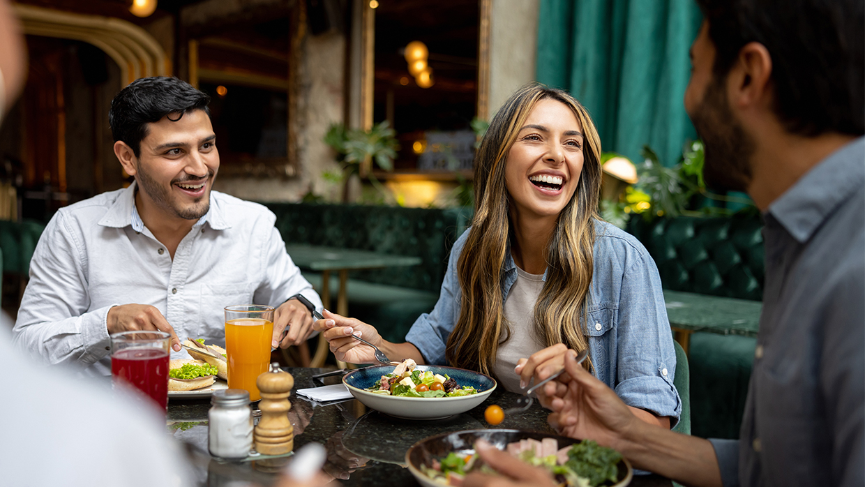 group of young people sharing food at a table in a restaurant