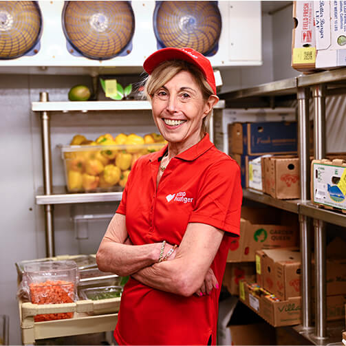 A woman in a red shirt stands confidently, smiling at the camera.
