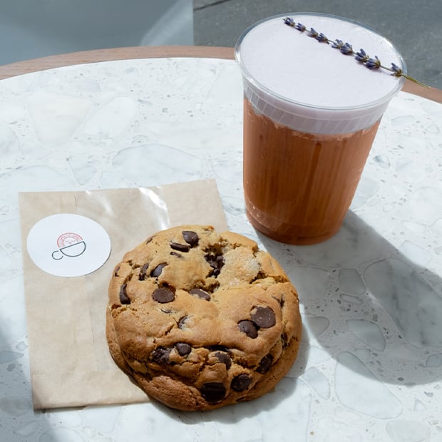 A picture with gourmet coffee and chocolate chip cookie.