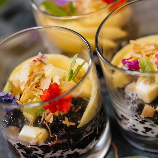 Three elegant glasses filled with a colorful assortment of fresh fruit and layered dessert, showcasing a delightful treat.