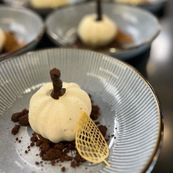 A plate featuring a dessert garnished with a single leaf, elegantly presented for a refined dining experience.
