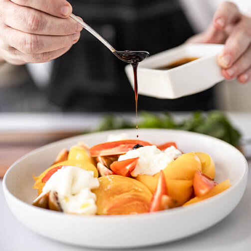 Fresh Caprese salad drizzled with balsamic vinegar, featuring vibrant tomatoes, mozzarella, and basil