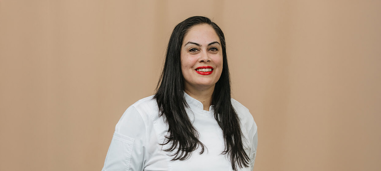 Photo of a female chef in a white uniform smiling