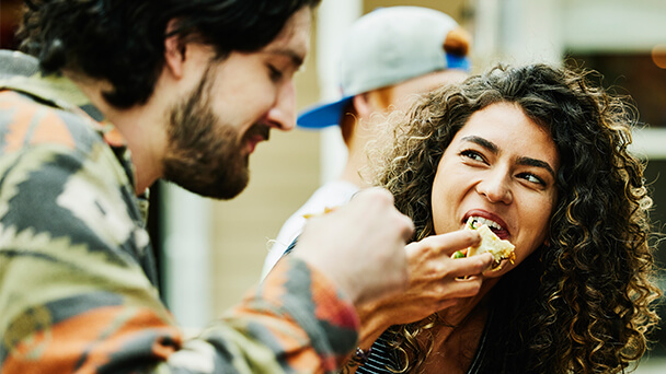 A man and woman sharing a pizza, enjoying a meal together in a cozy setting.