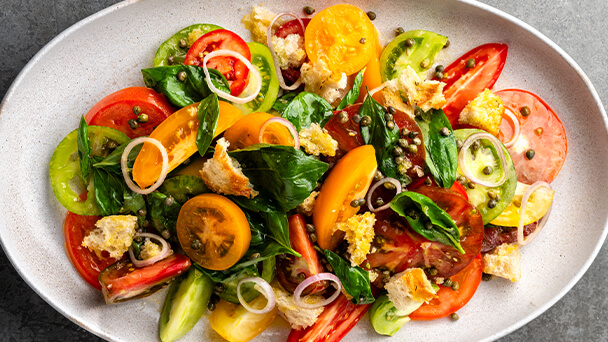 A colorful plate of fresh salad featuring tomatoes, onions, and a variety of other vegetables.