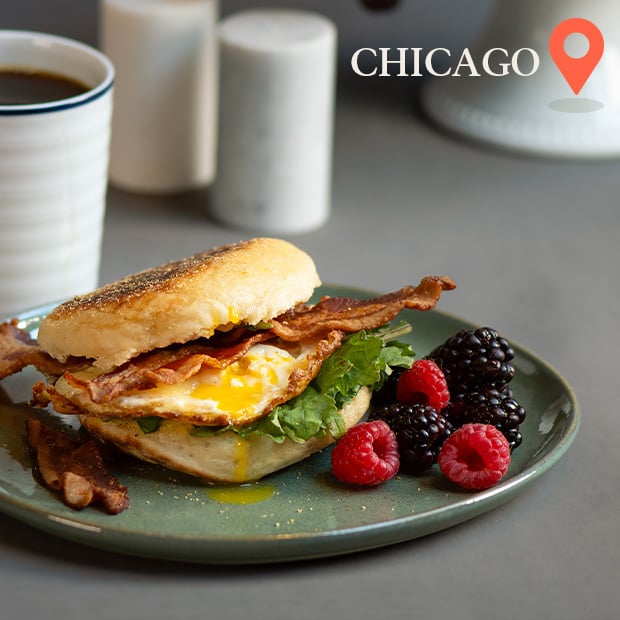 Bacon, egg and cheese on an english muffin with a side of fruit