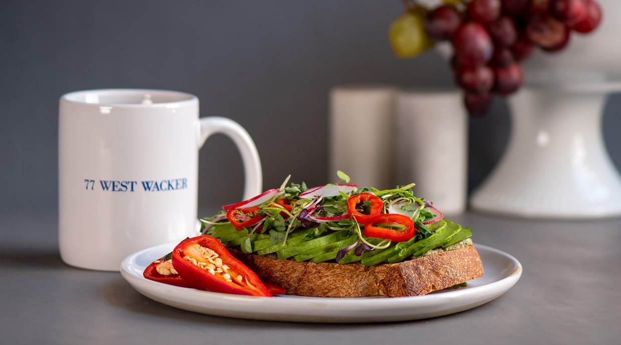 avocado toast topped with microgreens red chili slices and radishes on a white plate