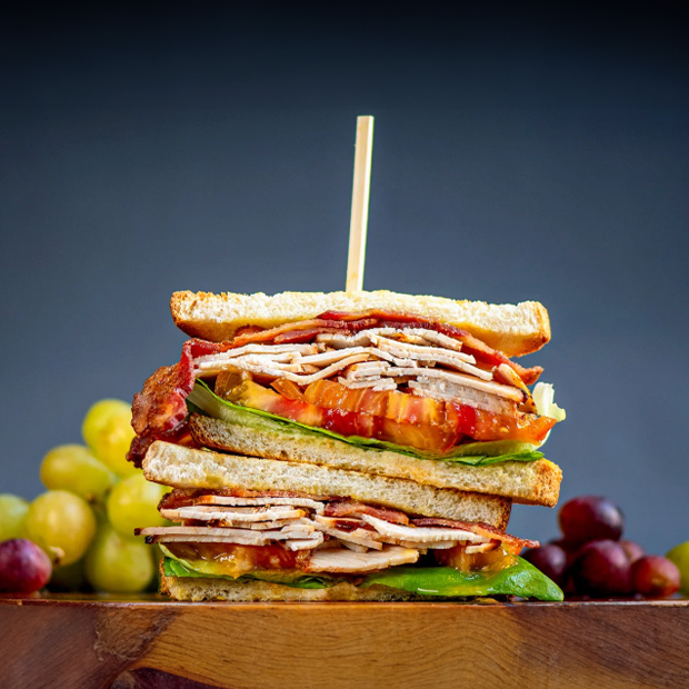 turkey club sandwich stacked with layers of turkey bacon tomato lettuce