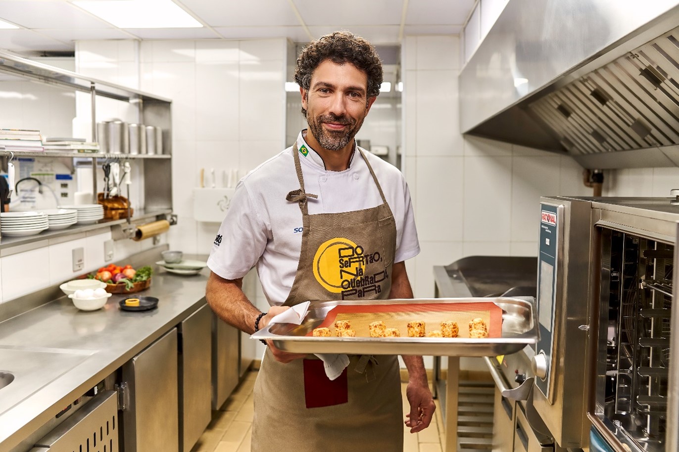 Chef segurando um prato com dadinhos de tapioca dentro e um pote com molho à parte 