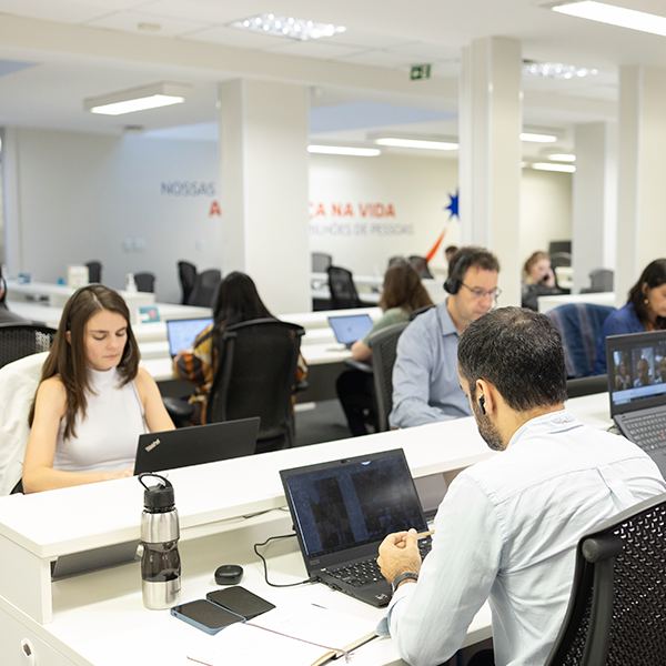 Colaboradores trabalhando em frente aos seus computadores em um ambiente corporativo.