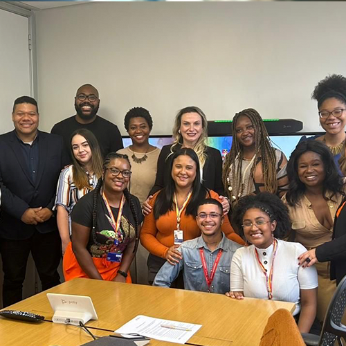 Grupo diverso de pessoas sorrindo e posando para uma foto em frente a uma mesa decorada.