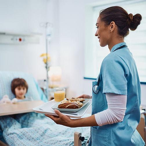 Woman serving food to a young boy at hospital