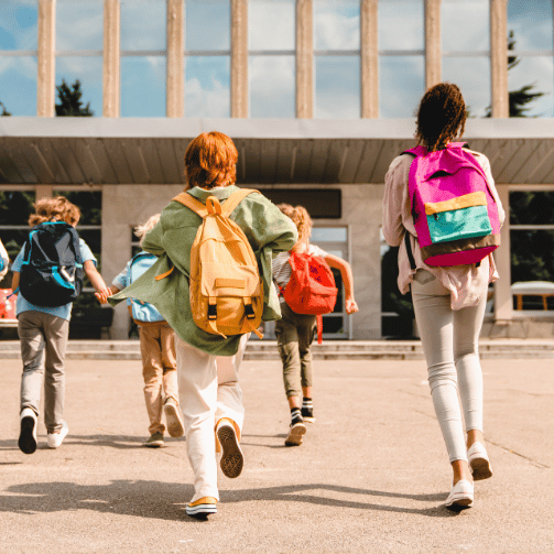 Copilot said:  Étudiants portant des sacs à dos colorés se dirigeant vers l’entrée d’une école par une journée ensoleillée.