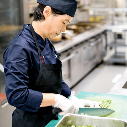 female chef in kitchen cutting vegetables