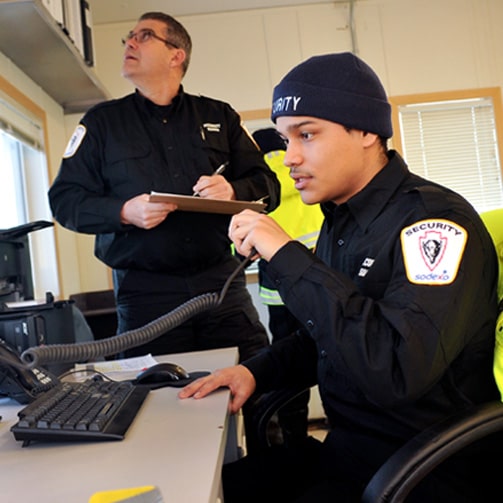 two men with uniform looking at a laptop