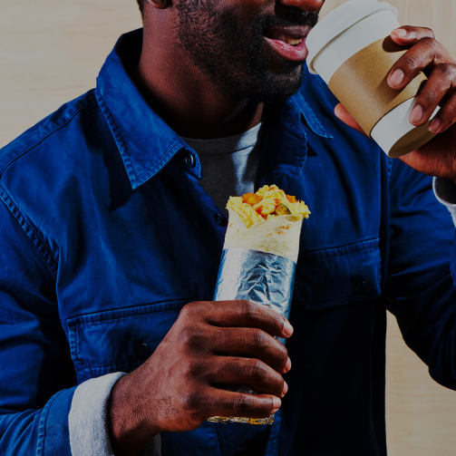 man eating wrap and coffee