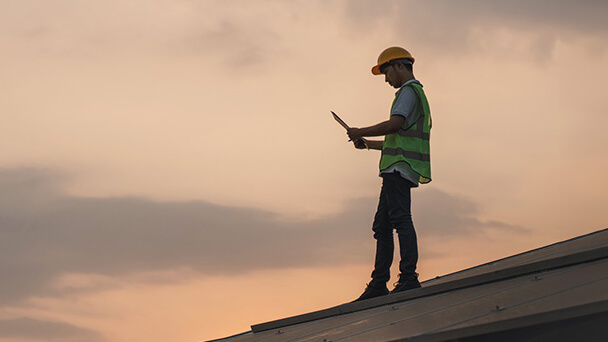 Engineer on a roof reviewing document