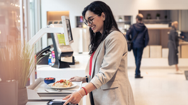 Young woman paying for food at self-service machine